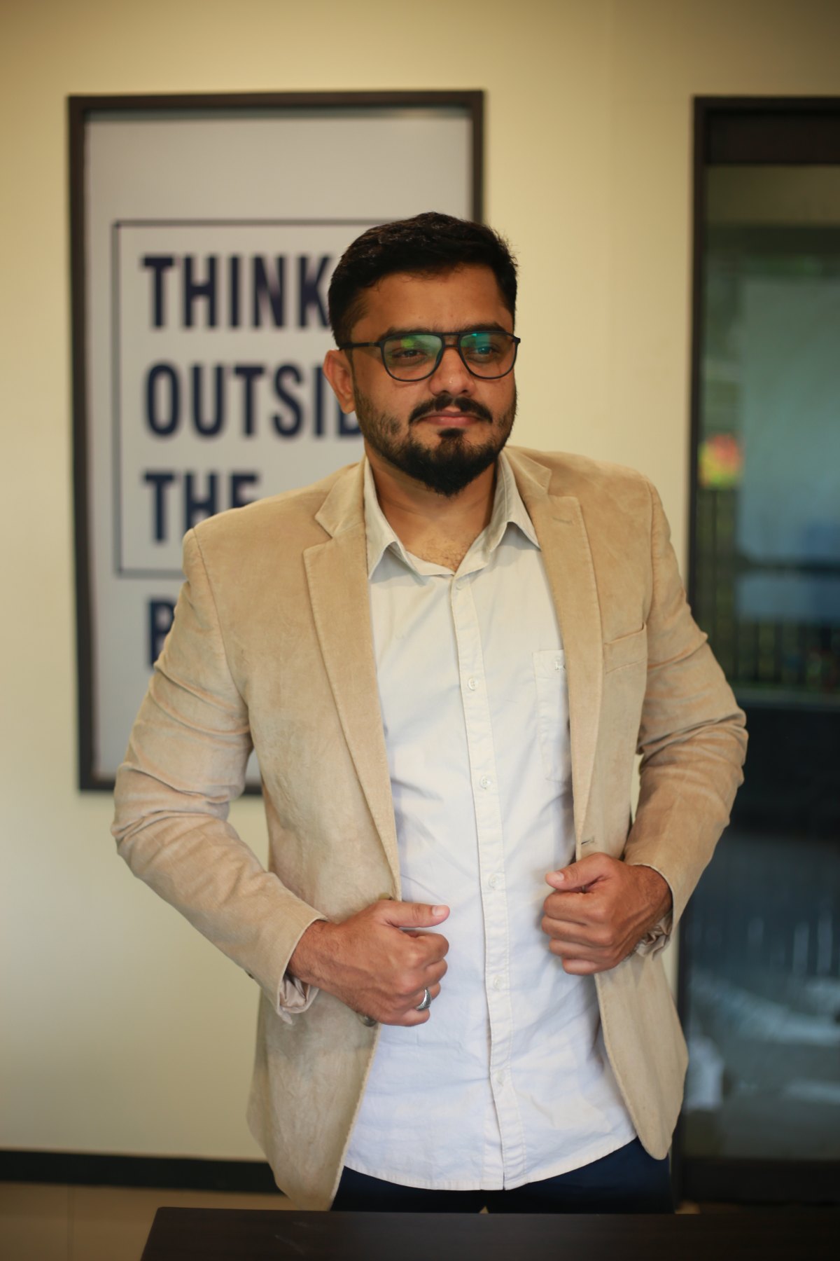 Ahmed Ashraf, founder of HAWKSEE, in a beige blazer at the HAWKSEE office